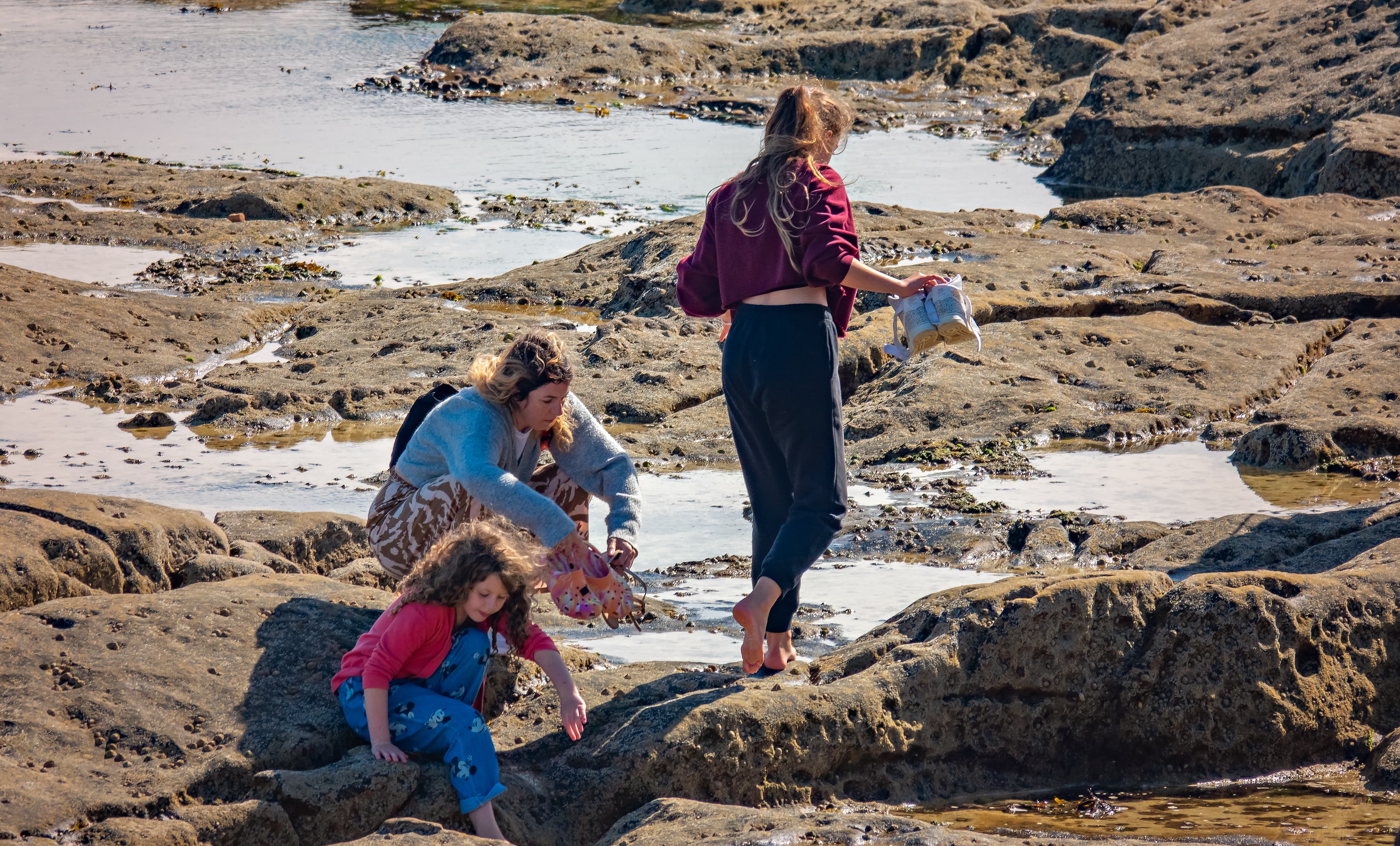 Women and children exploring rocks by the coast
